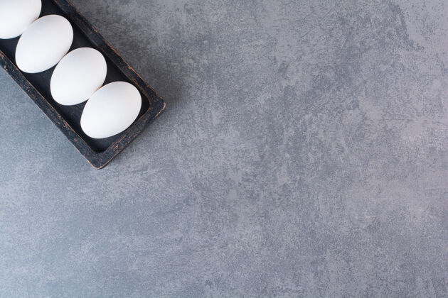 生的新鲜的生鸡蛋放在石桌上白复制空间顶视图