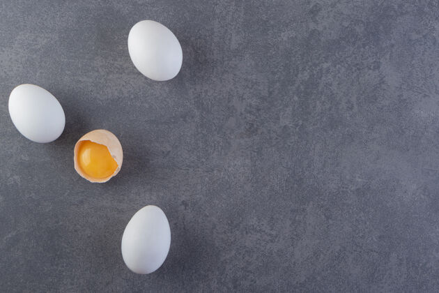 健康白色生鸡蛋和碎鸡蛋放在石桌上平面背景蛋壳
