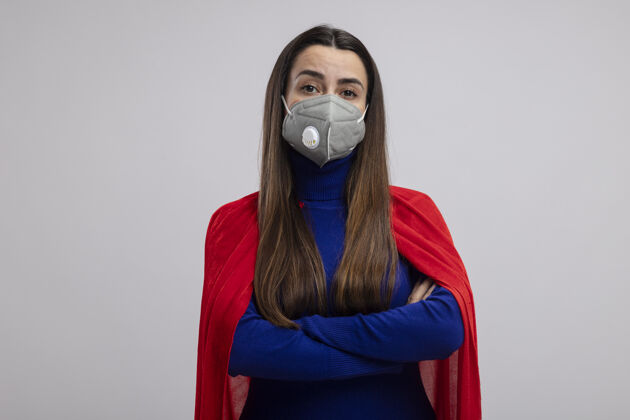 医疗自信的年轻超级英雄女孩戴着医用口罩双手交叉隔离在白色面具手年轻