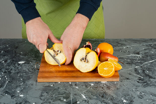 切男手切熟透的木瓜放在桌上的木板上有机手套烹饪