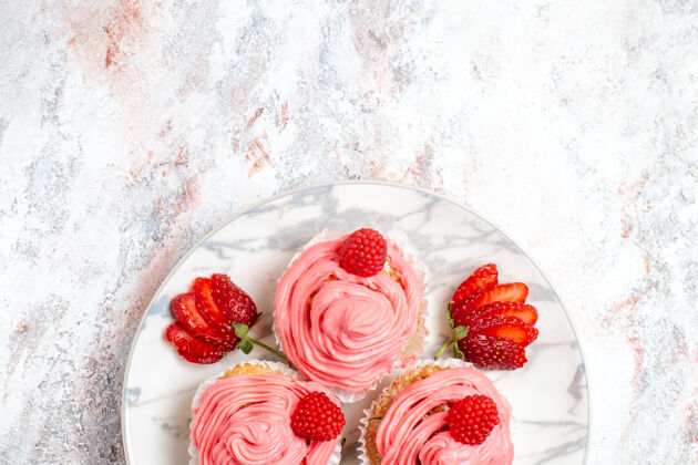奶油白色表面上有新鲜浆果的粉色草莓蛋糕俯视图浆果覆盆子水果