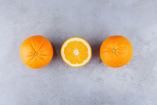 整个把整个橙子和切成片的橙子放在石桌上切片水果可口