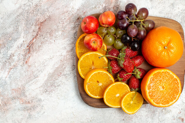 成熟白色表面上新鲜水果成分橙子葡萄和草莓的俯视图健康葡萄饮食
