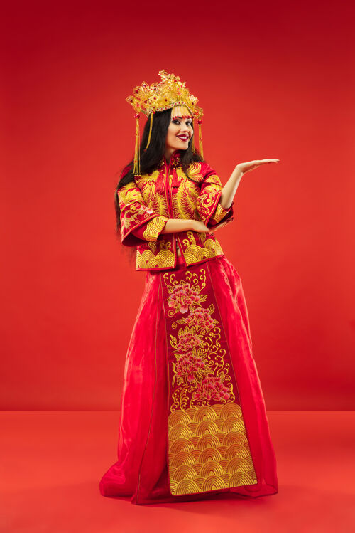 脸中国传统的优雅女子在摄影棚的红色背景美丽的女孩穿着民族服装中国新年 优雅 优雅 表演者 表演 舞蹈 女演员 服装的概念微笑情感肖像