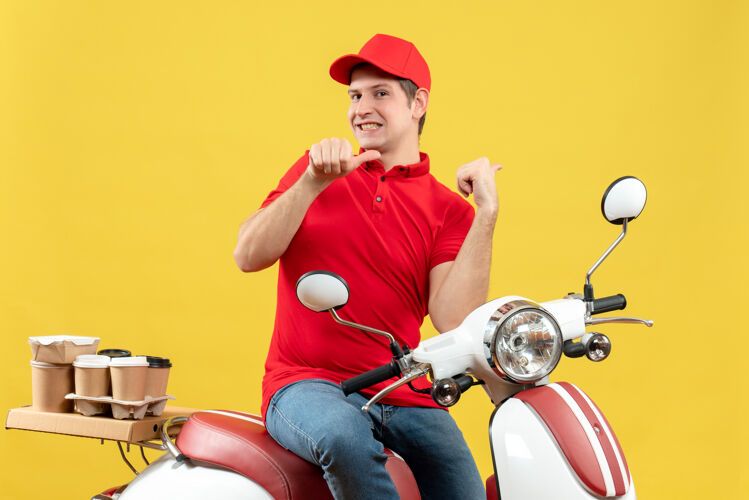 摩托车俯视图：微笑的年轻人穿着红色上衣 戴着帽子 指着黄色的墙上传递命令人车成人