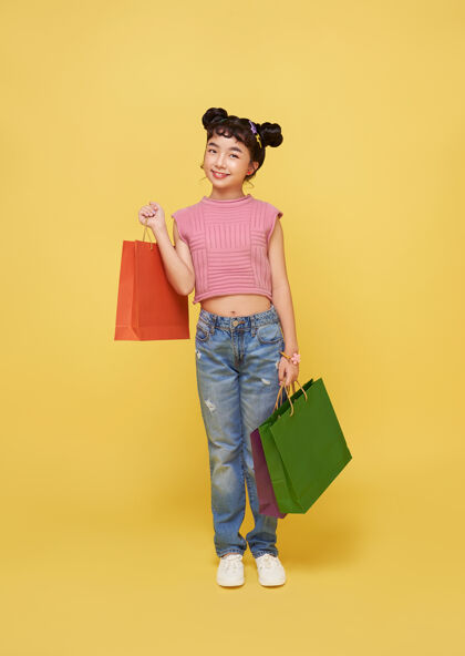 购物快乐快乐的亚洲孩子喜欢购物 她在购物中心拎着购物袋青年西班牙裔包