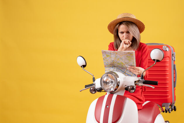 车辆前视图困惑美丽的女孩骑着轻便摩托车与红色手提箱举行地图微笑快乐音乐