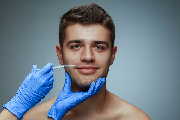 健康在灰色工作室背景上隔离的年轻人的特写肖像填充手术程序男人的健康和美丽的概念 美容 自我护理 身体和皮肤护理抗衰老嘴唇皮肤美容