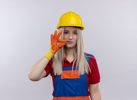 金发高兴的年轻金发工程师建设者穿制服的女孩戴着手套在孤立的白色空间与复制空间做ok标志女孩空间工程师