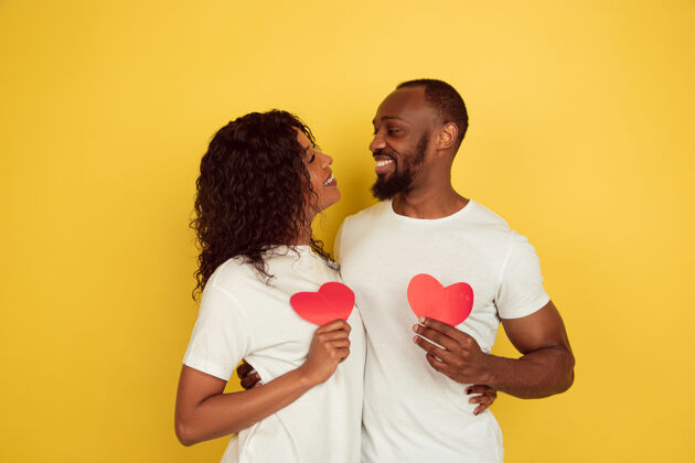 亲吻捧着红色的心情人节庆典 黄色工作室背景上的一对快乐的非洲裔美国夫妇人类情感的概念 面部表情 爱情 关系 浪漫的节日情人节情人非洲