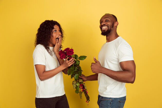 女孩花为微笑情人节庆祝 快乐的非洲裔美国夫妇隔离在黄色工作室背景人类情感的概念 面部表情 爱 关系 浪漫的节日男朋友情人一天