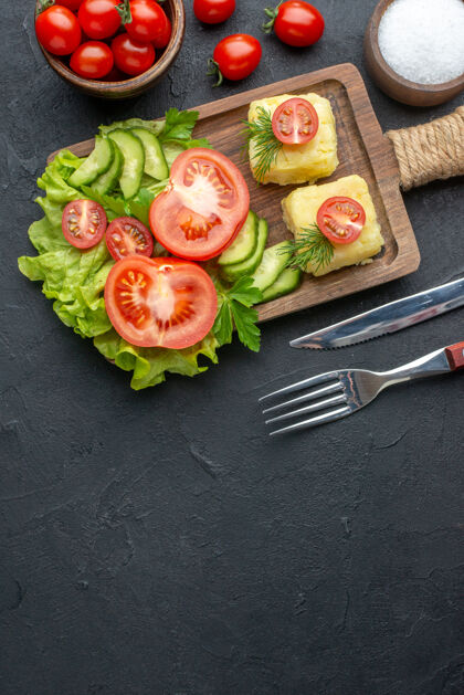 黄瓜切好的新鲜西红柿和黄瓜的垂直视图木板上的奶酪餐具黑色表面上放盐蔬菜盐食物