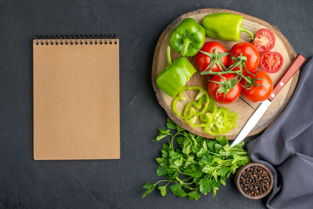 健康新鲜西红柿和青椒在木板笔记本上黑色表面的顶视图蔬菜食物沙拉