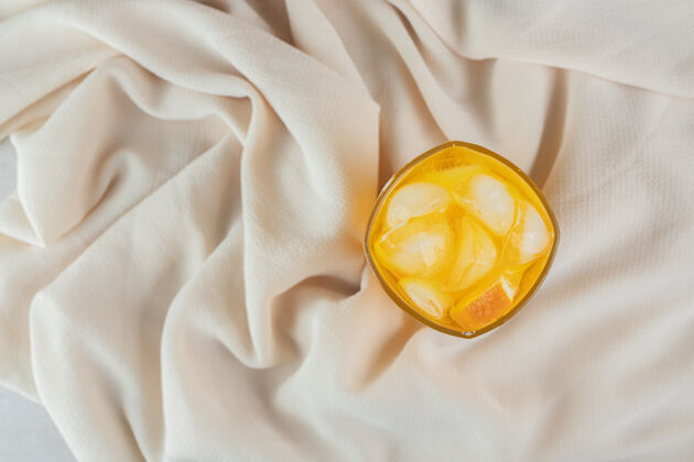 冰一杯橙汁加冰块放在棉布上柑橘刷新水果