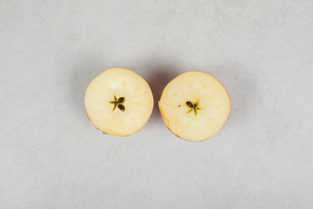 剁碎两个半切的红苹果在灰色的表面上水果苹果配料