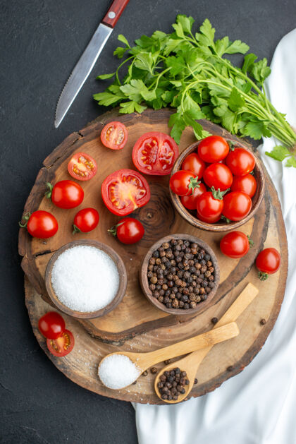 根类蔬菜新鲜西红柿和香料在碗里的垂直视图勺子在木板上的黑色表面碗胡椒营养