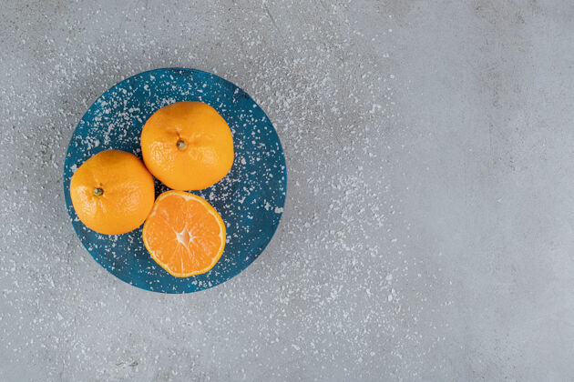 切片蓝色的盘子上覆盖着椰子粉和橘子在大理石表面配料有机天然