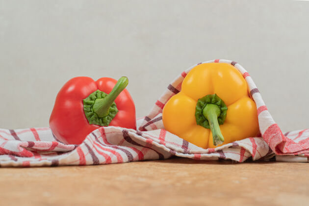 自然两个五颜六色的辣椒躺在桌布上食物有机大理石