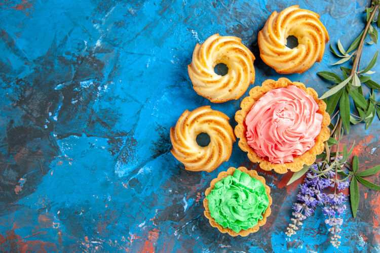 小馅饼小馅饼的俯视图 蓝色表面上有粉色和绿色的奶油色紫色花朵花束鲜花浪漫