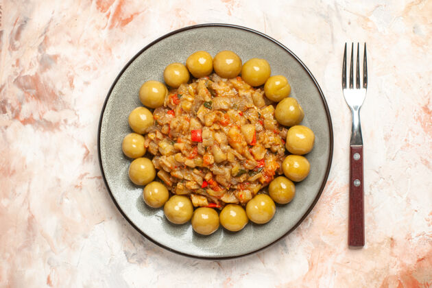 膳食烤茄子沙拉和腌李子在裸体表面的叉子上的顶视图盘子李子玉米