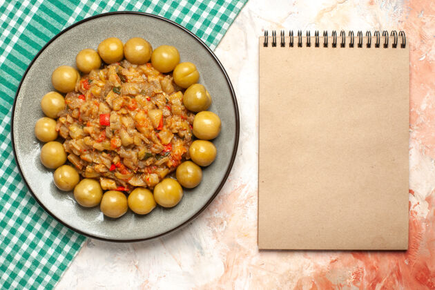 膳食烤茄子沙拉和腌李子在绿松石白格子表面的盘子上的俯视图裸体表面的布记事本裸体泡菜盘子