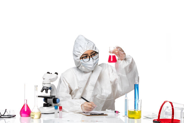 实验室外套正面图身着特殊防护服的女化学家拿着淡白色办公桌上的红色溶液科维化学病毒实验室浅白色健康保持
