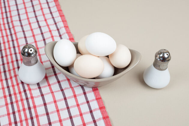 生的几只新鲜的鸡蛋放在桌布上的灰色盘子里青椒未经料理的家禽