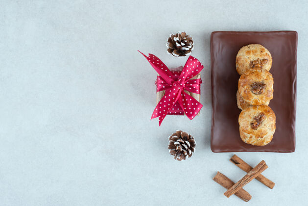 松果一盘黑色的饼干 里面有圣诞小礼物和松果肉桂深色坚果