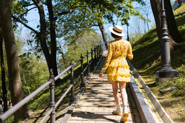 成人穿着黄色夏装 戴着帽子 走在公园小路上的户外时尚写真时尚女士肖像