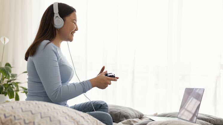 游戏在笔记本电脑上玩电子游戏的女孩控制器水平耳机