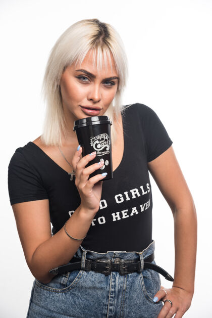咖啡年轻女子拿着一杯咖啡站在白色的墙上 表情严肃严肃表达成人