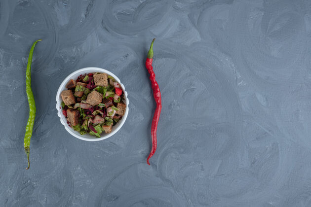 上等一碗混合沙拉在两个胡椒中间的大理石桌上干皮美味碗