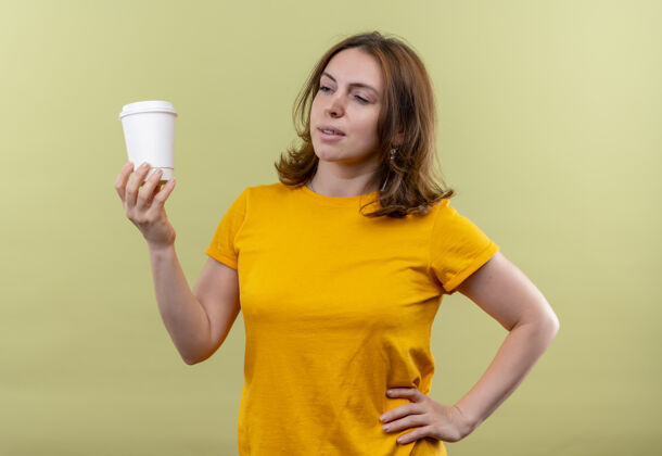 休闲在与世隔绝的绿地上 自信的年轻休闲女士手放在腰上拿着塑料咖啡杯年轻塑料自信