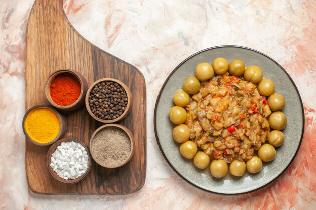 香料烤茄子沙拉和腌李子的顶视图 放在盘子里 切菜板上的香料放在裸体表面豆类种子盘子