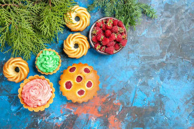 香料树莓蛋糕 小馅饼 饼干和蓝色表面有浆果的碗的俯视图覆盆子蛋糕可食用水果浆果