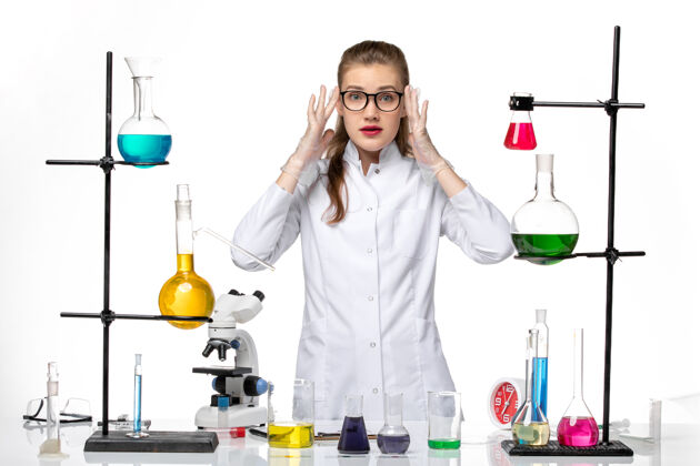 医疗前视图穿着医疗服的女化学家在白色办公桌上用不同的溶液处理化学大流行的病毒化学观点女化学家