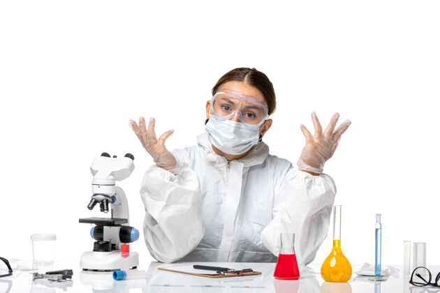 健康正面图：女医生穿着防护服 戴着口罩 坐在白色办公桌上 用解决病毒的药物来预防健康大流行人套装白人