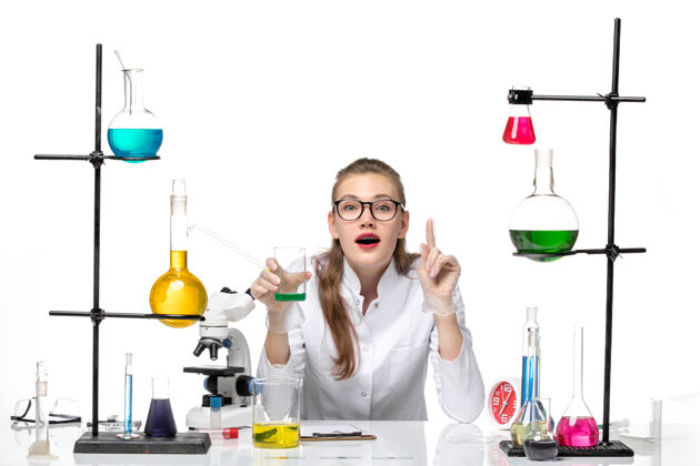 实验室前视图穿着医疗服的女化学家拿着一个白色背景上的装有溶液的烧瓶化学大流行健康病毒健康实验女化学家