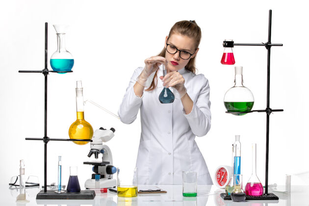 观点前视图身着医疗服的女化学家在工作过程中用白色背景化学溶液对大流行性冠状病毒过程科学医生