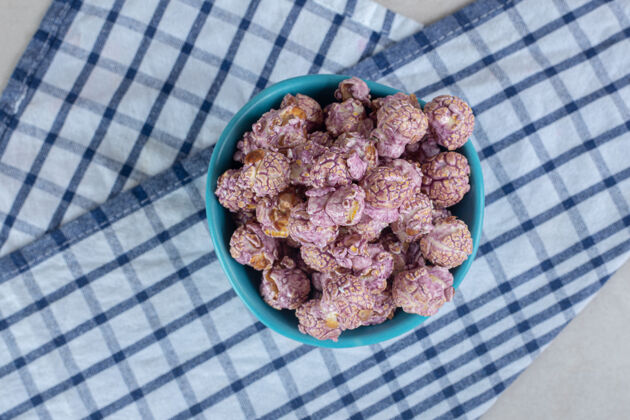 毛巾蓝色的碗放在折叠的毛巾上 在大理石桌上放满了涂着糖果的爆米花香精玉米爆米花