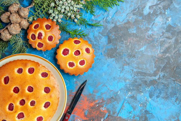 瓢虫树莓蛋糕的俯视图 蓝色表面上有树枝和刀子刀柑橘蛋卷