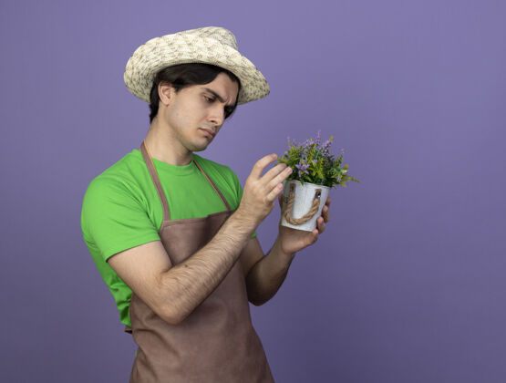 花想着穿着制服的年轻男园丁戴着园艺帽拿着花盆看花儿思想男紫色