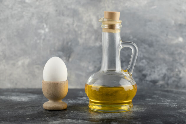 饮食一个木制鸡蛋杯 里面有煮熟的鸡蛋和一瓶玻璃油支架新鲜早餐
