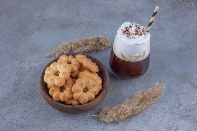 稻草一碗甜饼干和一杯咖啡放在大理石表面饼干奶油杯子
