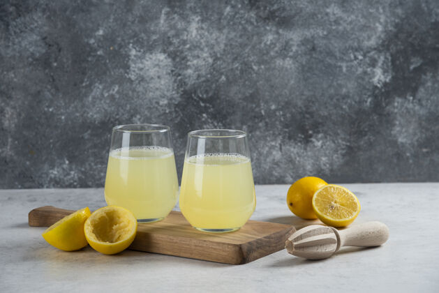 切片在木板上放两杯新鲜柠檬汁玻璃水杯子