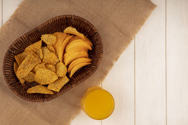 袋子在一张米色木桌上 一块布袋上放着一桶美味的脆薯片 一杯橙汁 还有复印空间薯条小吃桶