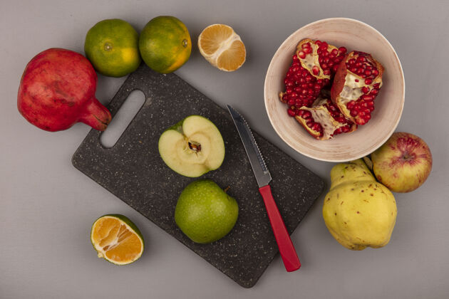 橘子黑色菜板上美味的苹果切片俯视图 刀子上放着石榴 碗里隔离着木瓜苹果和橘子木瓜水果黑