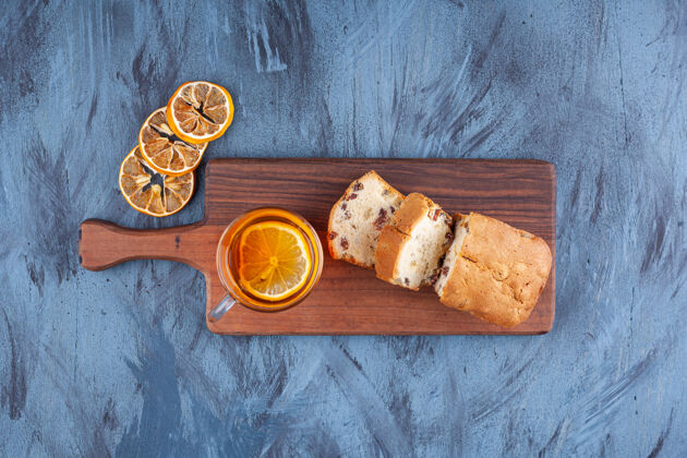 面包把自制的蛋糕切成薄片 葡萄干和一杯茶放在木砧板上蛋糕面包木板