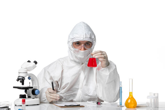 面罩正面图：男医生穿着防护服 戴着面罩 因为在浅白的空间里有一个装有红色溶液的瓶子溶液化学医疗