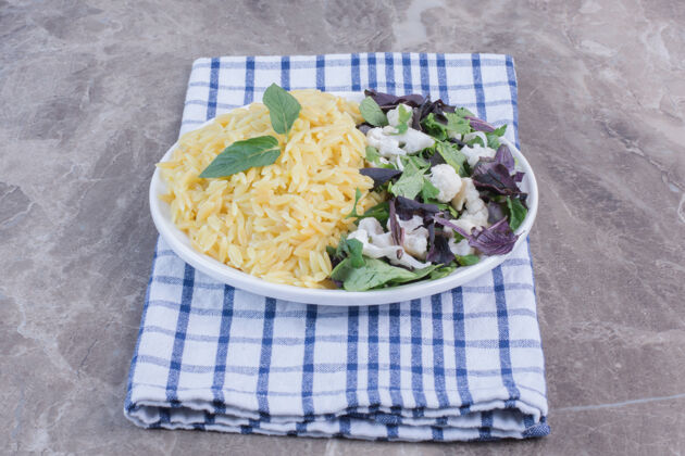 沙拉一盘米饭 配上苋菜 罗勒和花椰菜的沙拉 放在大理石表面的折叠毛巾上米饭食欲蔬菜